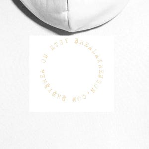 May include: Back view of a white hoodie. A circular logo in gold reads "BABYBREALAWRENSON.COM ON ETSY". The hoodie is presented against a white backdrop.