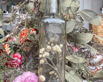 Bellissima bottiglia in vetro trasparente con decorazione di fiori secchi.