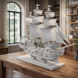 Puede incluir: Maqueta blanca detallada de un barco con múltiples mástiles y velas, apoyada sobre una base blanca. El barco presenta intrincadas tallas y un casco detallado, mostrando un diseño de velero clásico. El modelo se exhibe sobre una mesa de madera.