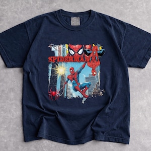 Puede incluir: Camiseta azul marino con un dise&ntilde;o de Spider-Man. El dise&ntilde;o presenta al superh&eacute;roe en rojo y azul, con la palabra "Spider-Man" en rojo. La camiseta est&aacute; hecha de un material suave.