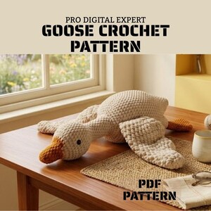 May include: A crochet goose toy with a cream-colored body and orange beak and feet. The text PRO DIGITAL EXPERT GOOSE CROCHET PATTERN and PDF PATTERN is visible. The goose is made of thick yarn with a visible stitch texture and small black eyes.