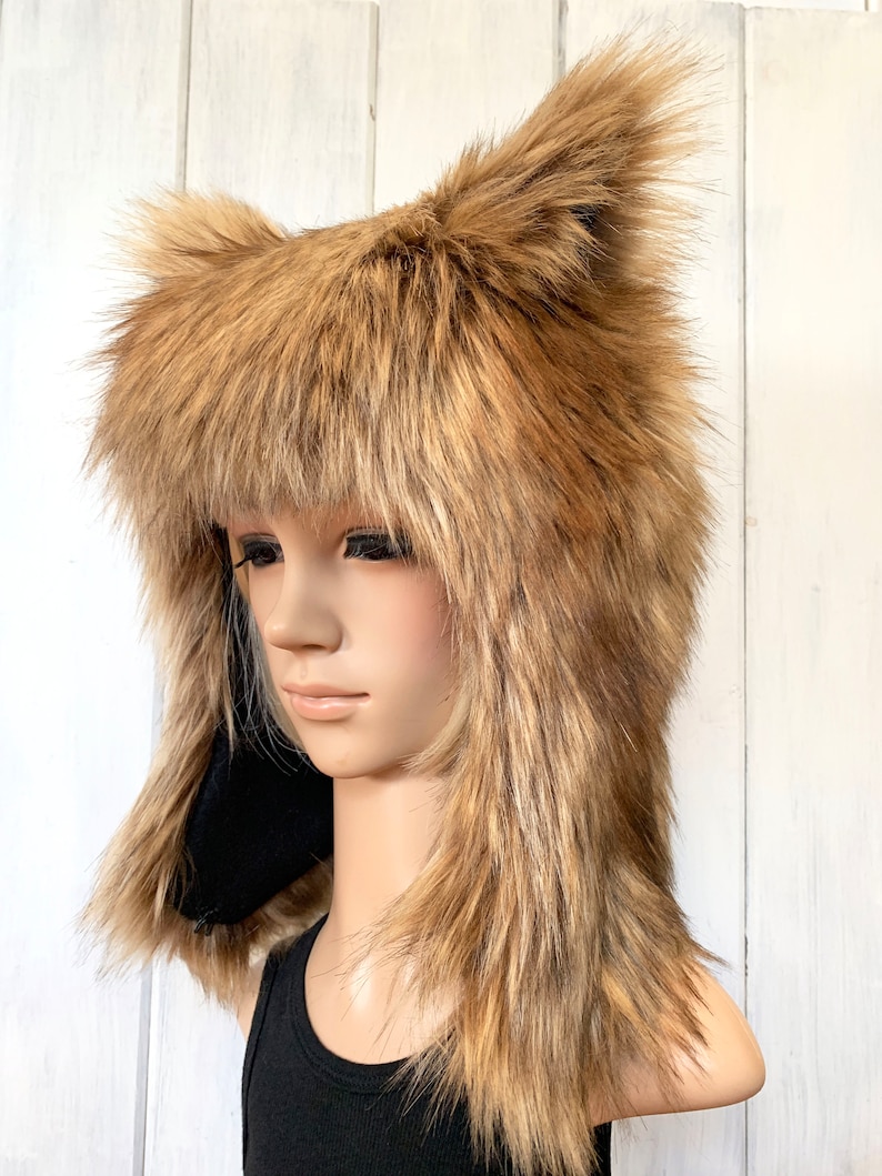 May include: A brown faux fur hat with long, floppy ears. The hat is made of soft, plush fur and has a black lining. The hat is worn by a mannequin with a black tank top.