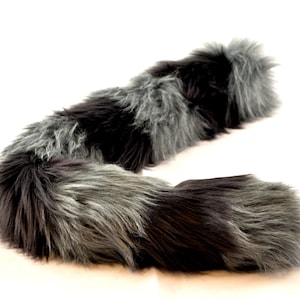 May include: A long, fluffy, gray and black faux fur tail. The tail is curled into a C shape and is perfect for adding a touch of whimsy to any costume.