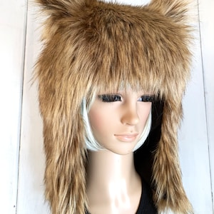 May include: A brown faux fur hat with long ear flaps. The hat is made of soft, fluffy fur and has a warm, cosy look.