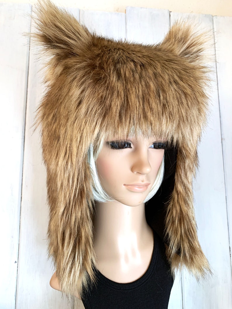 May include: A brown faux fur hat with long ear flaps. The hat is made of soft, fluffy fur and has a warm, cosy look.