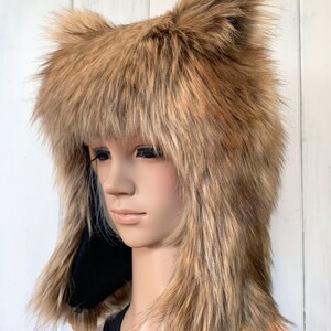 May include: A brown faux fur hat with long, floppy ears. The hat is being worn by a mannequin with long, straight hair.