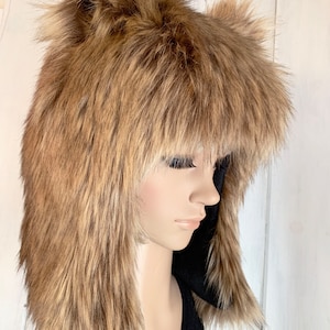 May include: A brown faux fur hat with long, floppy ears. The hat is worn on a mannequin's head.