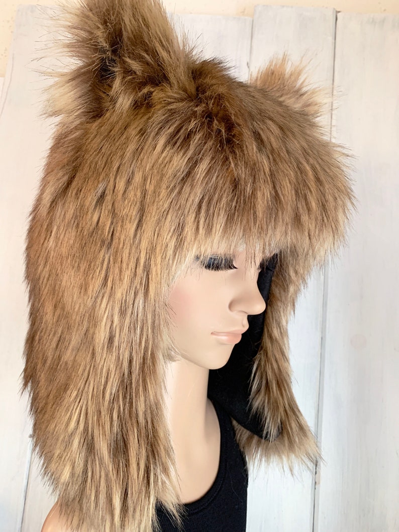 May include: A brown faux fur hat with long, floppy ears. The hat is worn on a mannequin's head.