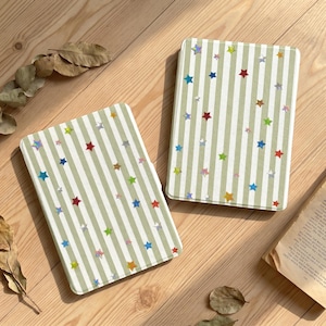May include: Two rectangular tablet cases featuring a light sage green and white vertical striped pattern. The surface of each case is decorated with numerous small, multi-colored holographic stars scattered across the striped background.