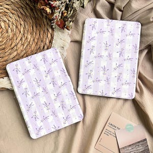 May include: Two lavender-themed tablet cases with a striped pattern and floral accents. The cases are light purple and white, with a delicate design of lavender sprigs. The cases are rectangular and appear to be made of a smooth material.