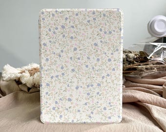 May include: A rectangular tablet case with a floral design. The case has a cream-coloured background with a delicate pattern of small blue, pink, and green flowers and vines. The case is designed to protect a tablet and adds a touch of style.