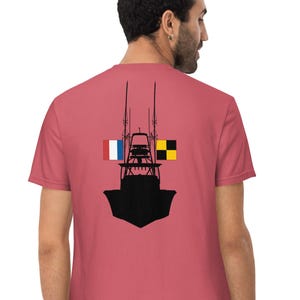 Op de afbeelding: Stofroze t-shirt met een zwart silhouet van een boot en twee vlaggen. Eén is de Franse vlag, de andere een geel-zwarte vlag. Het shirt is een casual stijl, geschikt voor dagelijks gebruik.