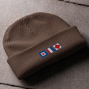 Peut inclure: Une tasse en céramique blanche avec une anse noire et l'inscription "But First, Coffee" en gras noir. La tasse est posée sur un fond flou, suggérant un cadre chaleureux.