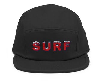 以下が含まれることがあります： 黒色のフラットブリムキャップ。前面に「SURF」の文字が赤色で刺繍されており、白と青のアクセントが施されています。サーフィンやビーチ愛好家向けのカジュアルなアクセサリーです。