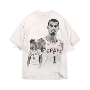 May include: White t-shirt with a black and white graphic of a basketball player in a Spurs jersey. The jersey displays the number 1 and the word "SPURS". The shirt has a crew neck and short sleeves.