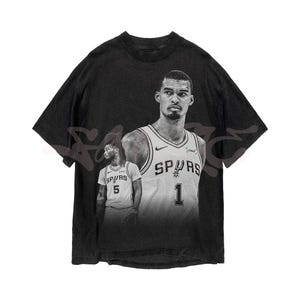 May include: Black graphic t-shirt featuring two basketball players in grayscale. The players are wearing Spurs jerseys with the numbers 1 and 5. The shirt has a vintage, distressed appearance.