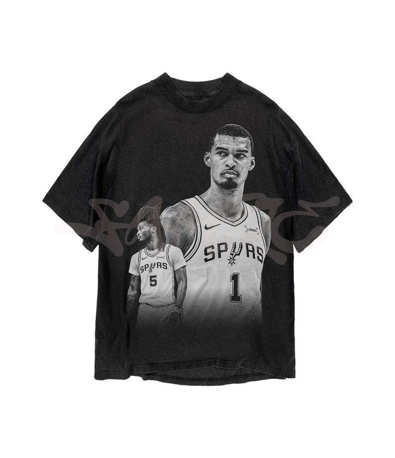 May include: Black graphic t-shirt featuring two basketball players in grayscale. The players are wearing Spurs jerseys with the numbers 1 and 5. The shirt has a vintage, distressed appearance.