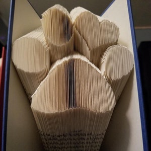 Peut inclure: Un livre dont les pages sont pliées en forme d'empreinte de patte. Le livre est ouvert et l'empreinte de patte est visible. Le livre a une couverture bleue.