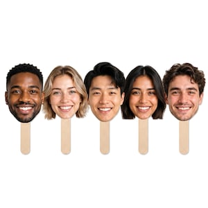 May include: Five individual face cutouts attached to light-coloured wooden sticks. Each cutout features a high-resolution, full-colour photograph of a smiling person's head and shoulders, showcasing a diverse range of facial features and hair styles.