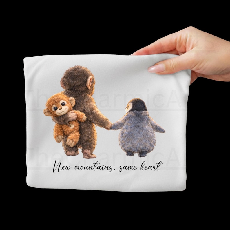 May include: White fabric featuring a whimsical illustration of a monkey holding a stuffed monkey and a penguin holding hands. The text "New mountains, same heart" is below the illustration.