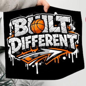 Puede incluir: Ilustración gráfica negra con las palabras "BUILT DIFFERENT" en blanco, con letras agrietadas, y una pelota de baloncesto naranja. El diseño incluye una flecha y acentos naranjas y blancos, con un efecto de salpicadura blanco.