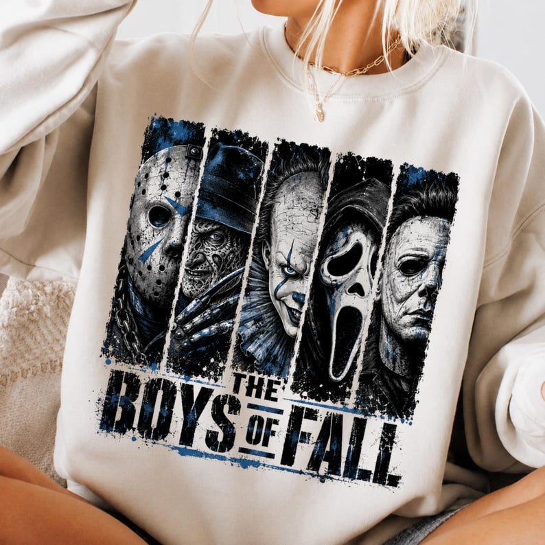 May include: A cream-colored crewneck sweatshirt featuring a graphic print of five horror movie characters arranged in vertical panels. Below the characters, the text reads THE BOYS OF FALL in a bold, distressed black font with blue accents.