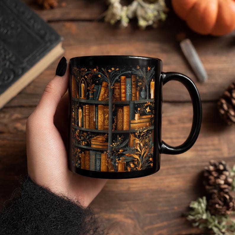 Puede incluir: Taza de cer&aacute;mica negra con una ilustraci&oacute;n detallada de una estanter&iacute;a llena de libros, velas y elementos bot&aacute;nicos. El dise&ntilde;o incorpora tonos dorados, marrones y azules sobre un fondo negro. La taza tiene un asa negra.
