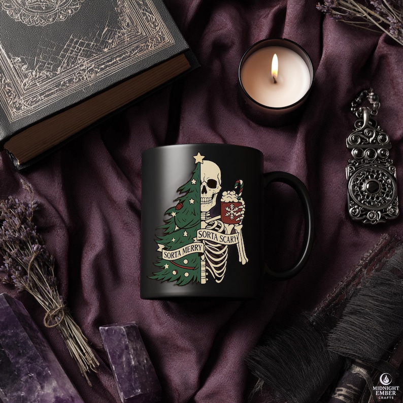 May include: Black ceramic mug featuring a skeleton design with a Christmas tree and the text "Sorta Merry Sorta Scary." The mug also has a candy cane and a cup of hot cocoa. The mug is surrounded by a candle, a book, and other decorative items.
