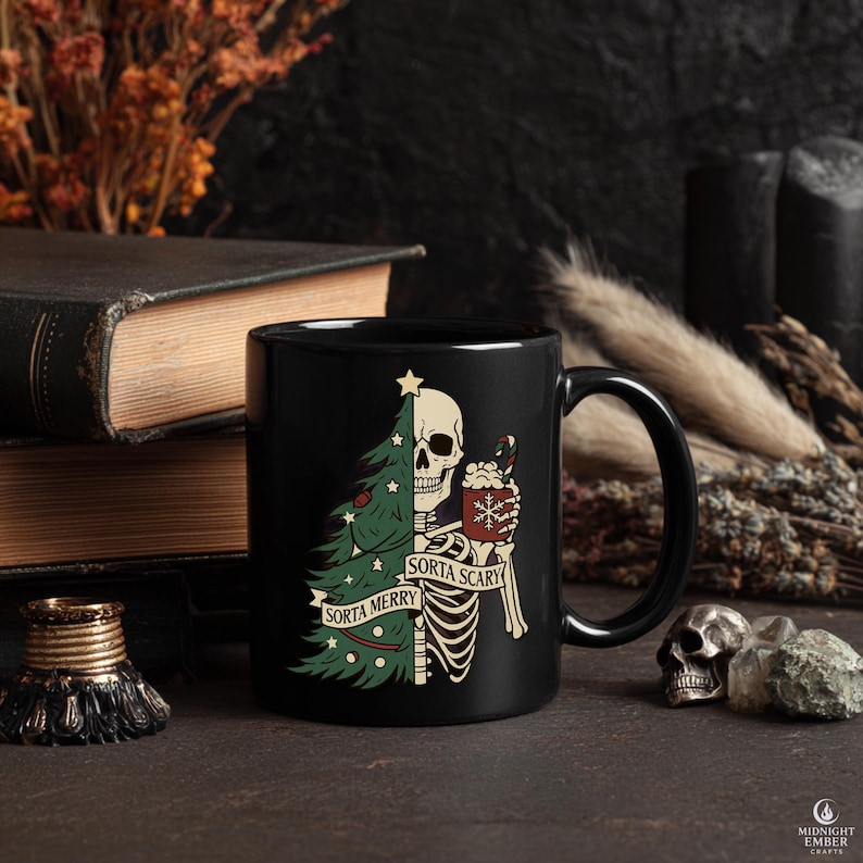 May include: Black ceramic mug with a humorous Christmas design. One side features a green Christmas tree, the other a skeleton holding a mug of cocoa. The text reads "Sorta Merry" and "Sorta Scary".
