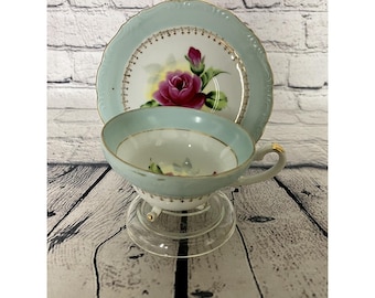 Taza de té vintage de porcelana azul japonesa con motivos de rosas pintadas a mano y detalles dorados.