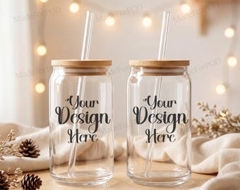 May include: Two clear glass beverage cups with bamboo lids and clear straws. The cups have the text "Your Design Here" in black script. The background includes fairy lights and decorative elements.