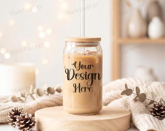 May include: A clear glass tumbler with a wooden lid and a clear straw, filled with a light brown beverage. The text "Your Design Here" is printed on the glass. The tumbler sits on a round wooden stand, with a cozy, neutral-toned background.