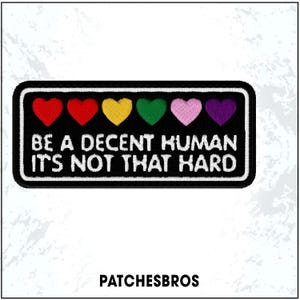 May include: A rectangular black patch with a white border features the text "BE A DECENT HUMAN IT'S NOT THAT HARD" in white. Above the text are six embroidered hearts in red, orange, yellow, green, pink, and purple. The brand name "PATCHESBROS" is at the bottom.