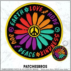 May include: Embroidered patch with a colorful daisy design featuring the peace symbol at the center. The patch includes the words "Earth, Love, Hope, Joy, Peace, Kindness" and a smaller matching keychain. The patch has a black background and a yellow border.