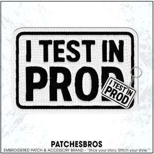May include: Embroidered patch with the text "I TEST IN PRO" in black on a white background, framed by a black border. A smaller keychain tag with the same text hangs from the patch. The brand name "PATCHESBROS" is at the bottom.