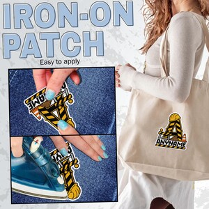 May include: An iron-on patch featuring a large letter A designed with yellow and black construction hazard stripes, a yellow hard hat, and orange traffic cones. The patch includes the text ANYNAME and is shown applied to a beige tote bag.
