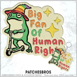 May include: Embroidered patch featuring a green frog riding a scooter, wearing a hat, and the text "Big Fan Of Human Rights." Includes a matching keychain. The patch has a cream-colored background with orange, yellow, and red text.