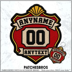May include: A shield-shaped embroidered patch and a matching keychain featuring a red background, black borders, and gold accents. The design includes the text ANYNAME on a banner, the number 00 in the center, and the text ANYTEXT on a lower banner.