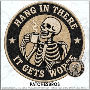 May include: A circular embroidered patch and matching keychain featuring a skeleton holding a steaming coffee mug. The design includes the text HANG IN THERE and IT GETS WORSE in beige lettering against a black background with two beige stars.