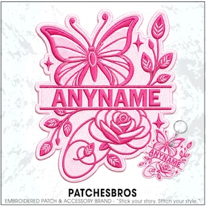 May include: A pink embroidered patch and matching keychain featuring a butterfly at the top and a rose at the bottom. Both items include a horizontal banner with the text ANYNAME centered in bold capital letters, surrounded by decorative vines.