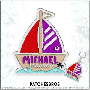 May include: Embroidered patch and keychain set featuring a sailboat design. The patch has a red sail, purple sail, and the name "MICHAEL JOHNSON". The keychain mirrors the design. The brand name "PATCHESBROS" is at the bottom.