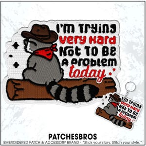May include: Embroidered patch featuring a raccoon wearing a cowboy hat and red bandana, sitting on a log. The patch reads "I'm trying very hard not to be a problem today." A matching keychain is also shown.