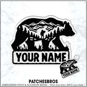 May include: A black and white embroidered patch and matching keychain featuring a bear silhouette filled with a mountain and forest landscape. The text "YOUR NAME" is embroidered in bold black letters on a white rectangular base at the bottom.