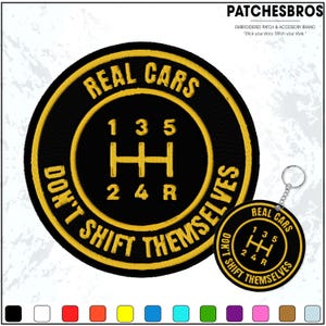 May include: Black and yellow embroidered patch and keychain set. The patch and keychain feature the text "REAL CARS DON'T SHIFT THEMSELVES" around a gear shift pattern. The patch and keychain are circular.