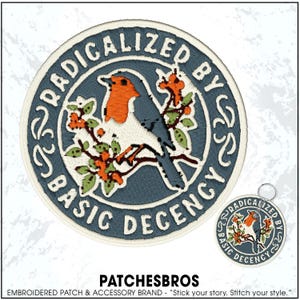 May include: A circular embroidered patch featuring a robin perched on a branch with orange flowers and green leaves against a blue background. The text RADICALIZED BY BASIC DECENCY is stitched in white along the border with decorative flourishes.