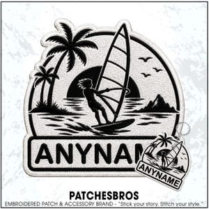 May include: A black and white embroidered patch and matching keychain featuring a windsurfer on the water with palm trees, a sun, and birds in the background. The design includes a rectangular banner at the bottom with the text ANYNAME.
