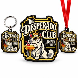 May include: A set featuring a keychain, a large embroidered patch, and an ornament with a red ribbon. Each item displays a cat wearing a crown and sunglasses, holding a cocktail, with the text The Desperado Club So Fun It Hurts.