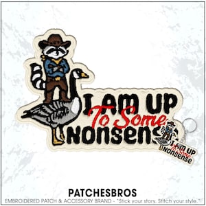 May include: Embroidered patch featuring a raccoon in a cowboy hat riding a goose, with the text "I AM UP To Some Nonsense." A small keychain with the same design is also visible. The patch has a cream-colored border.