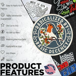 May include: A circular embroidered patch featuring a robin perched on a branch with orange berries, surrounded by a blue border with the text "RADICALIZED BY BASIC DECENCY" in white. The patch is displayed alongside other patches and text.