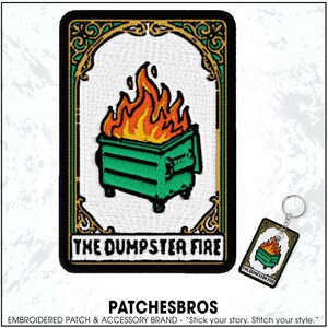 May include: Embroidered patch featuring a green dumpster engulfed in orange and yellow flames. The patch has a gold border and the words "THE DUMPSTER FIRE" are displayed at the bottom. A matching keychain is also visible.
